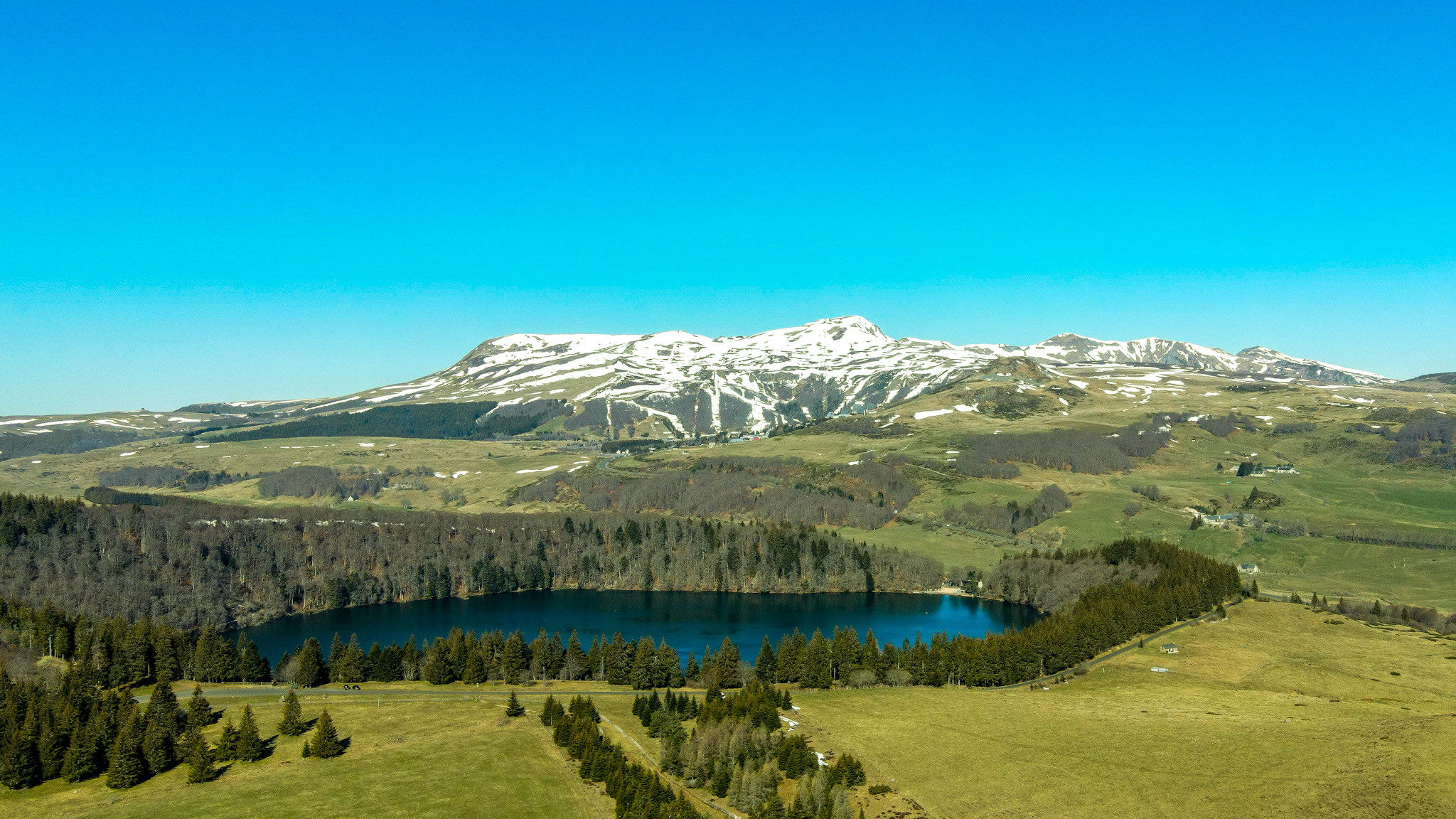 Le Lac Pavin et la station de Super Besse enneigée au Printemps